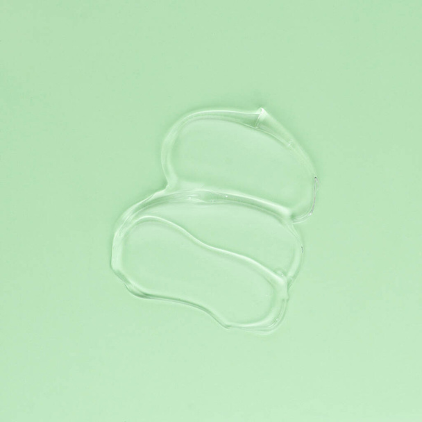 Mancha de crema transparente para la cara y el cuerpo sobre un fondo verde - Foto, imagen