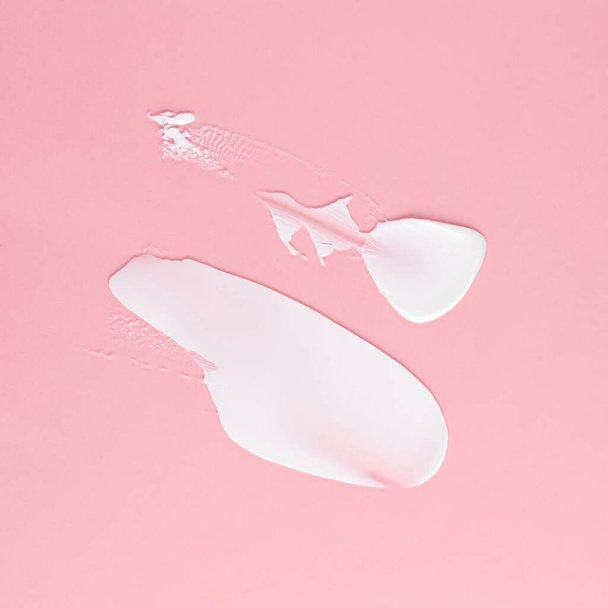 Mancha de crema blanca para la cara y el cuerpo sobre un fondo rosa - Foto, imagen