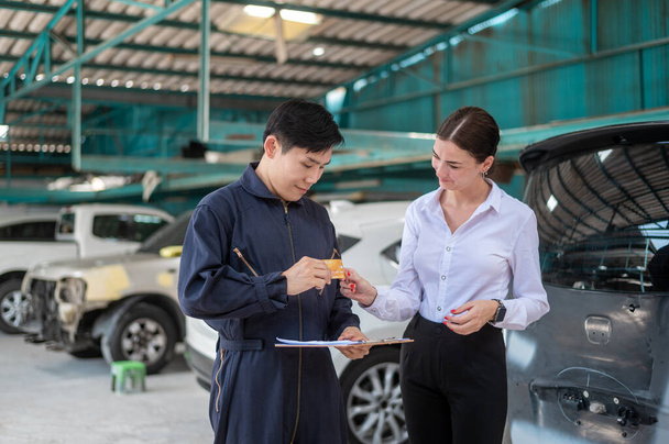 A young Caucasian woman paying via credit card to mechanic man in repair service shop - Fotó, kép