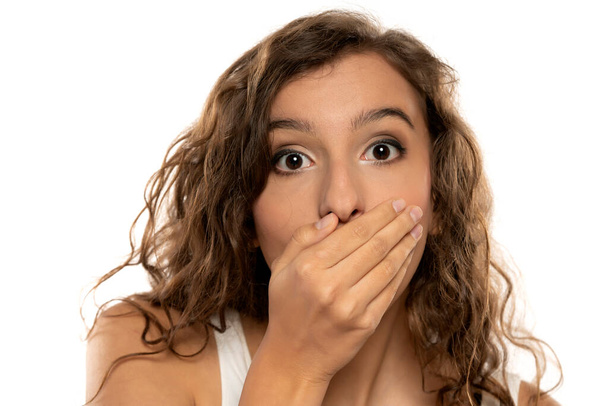 young beautiful shocked  girl covering her mouth with her hands on a white studio background - Foto, Imagem