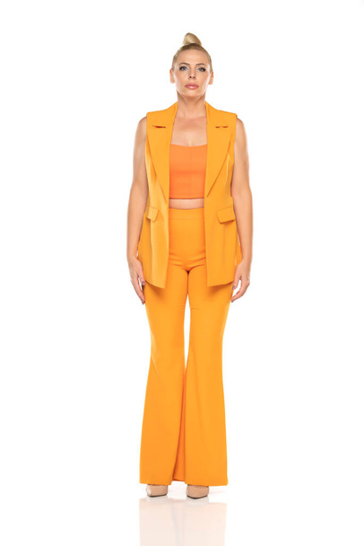 Middle aged senior woman in yellow sleevless jacket and trousers posing on a white studio background - Valokuva, kuva