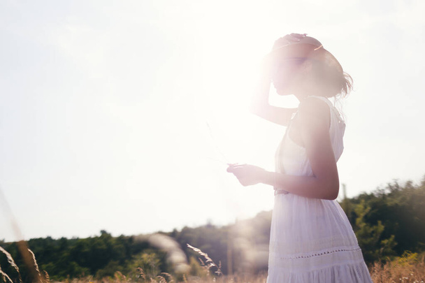 Beautiful girl in a linen dress in a wheat field. Summer vacation, traveling. Bohemian, modern hippie style. - Fotoğraf, Görsel
