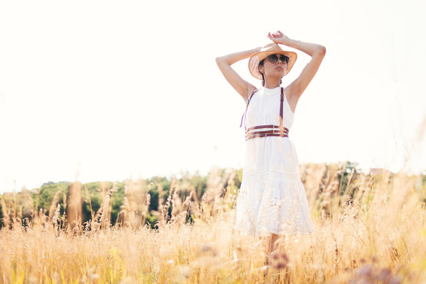 Beautiful girl in a linen dress in a wheat field. Summer vacation, traveling. Bohemian, modern hippie style. - Фото, зображення