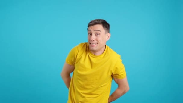 Відео в студії з блакитним тлом чоловіка кидає конфетті на себе, коли він посміхається в екстазі - Кадри, відео