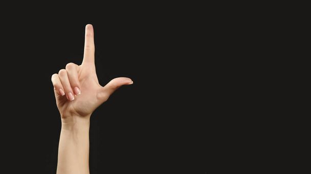 Advertising hand. Attention gesture. Woman pointing finger up framing blank area isolated on dark black empty space promotional background. - Фото, зображення