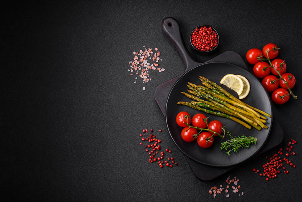 Délicieux petit déjeuner nutritif composé d'asperges, tomates, sel, épices et herbes sur fond de béton foncé - Photo, image