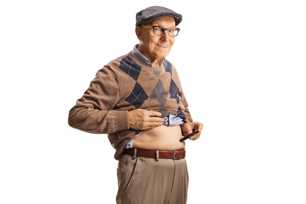 Senior man poking abdomen with an insulin pen isolated on white background - Foto, imagen