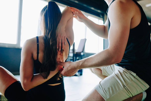 Professional Physiotherapy Male Chiropractor Offers Expert Assistance to Woman in the Gym. Holistic approach to health Female receives professional assistance from a male therapist in the gym - Photo, image