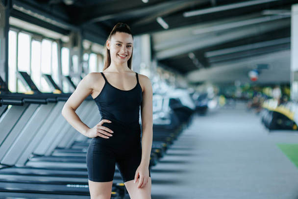 stunning gym portrait captures the beauty and athleticism of a young woman as she poses with poise and grace. Her contagious laughter and joyful demeanor radiate a sense of happiness - Foto, imagen