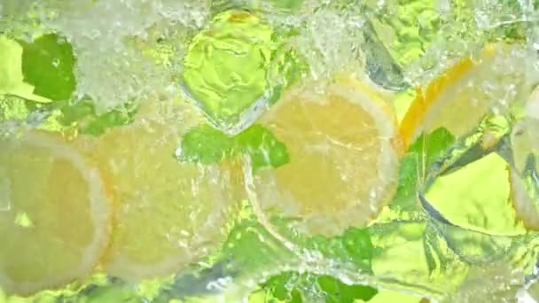 Super Slow Motion Shot of Water Wave Salpicando en rodajas de limón, cubitos de hielo y hojas a 1000fps. Filmado con cámara de cine de alta velocidad a 4K. - Imágenes, Vídeo