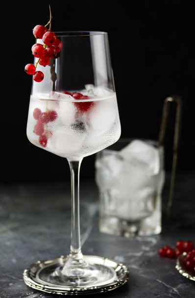 Close up of iced red currant drink. Fresh ice cold fruit cocktail in wine glass, refreshing summer red currant berry drink with on stone concrete background, front view, copy space. Red currant water - Foto, Imagem