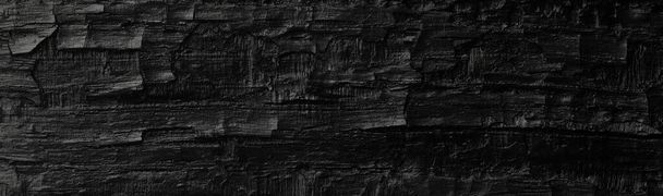 Dunkelschwarzer Hintergrund aus grob verbranntem Holz, Ruß und Asche. Textur verbrennen. - Foto, Bild