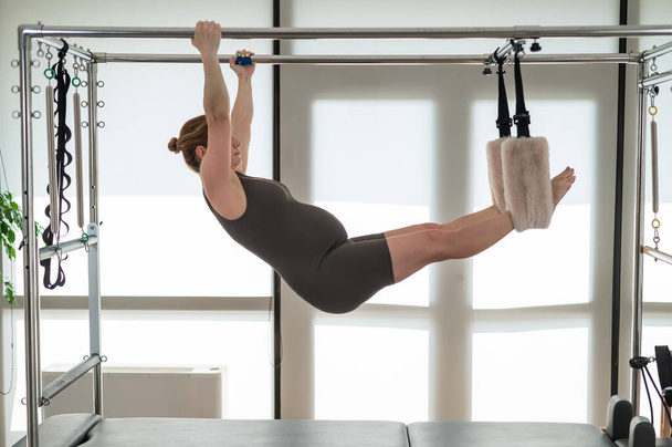 Pregnant woman doing pilates on a reformer - Foto, afbeelding