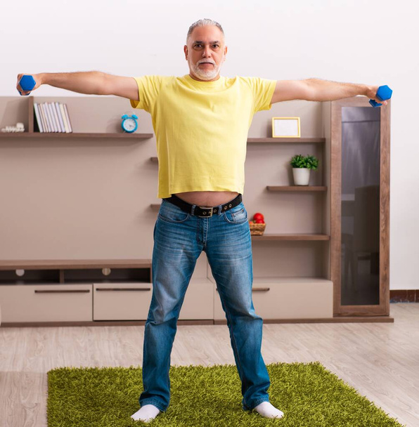 Old man doing sport exercises at home - Foto, Bild