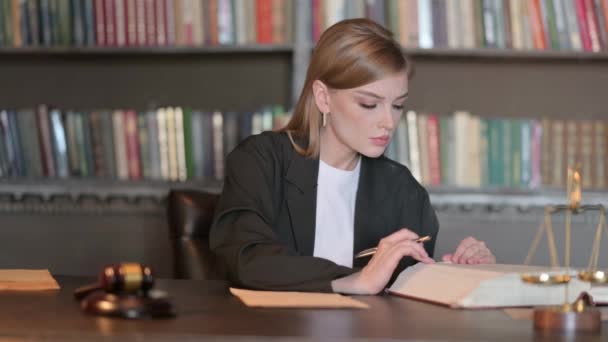 Молода жінка юрист Працює над юридичними документами в офісі - Кадри, відео