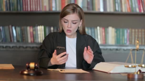 Молода жінка-юрист шокована новинами про невдачу на телефоні в офісі - Кадри, відео