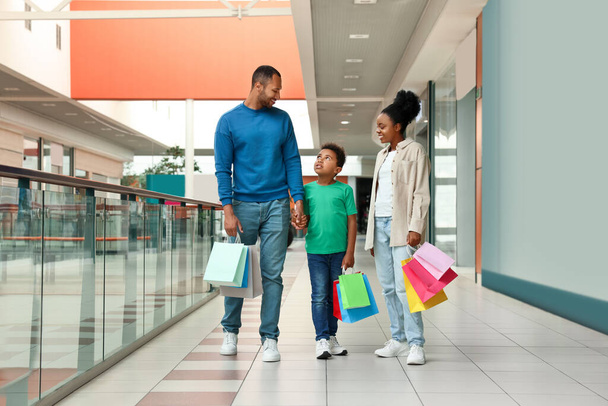 Family shopping. Happy parents and son with colorful bags in mall - Photo, image