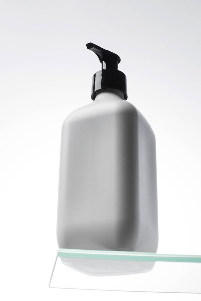 Een mock-up van een witte dispenser met cosmetica met plaats voor uw logo op de plank. Douchegel, shampoo. Huidverzorging. - Foto, afbeelding
