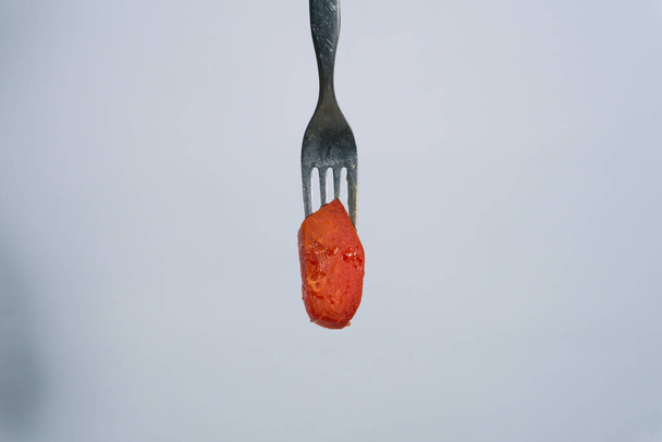 красный фрукт папайи, сладкий на вилке на изолированном фоне - Фото, изображение