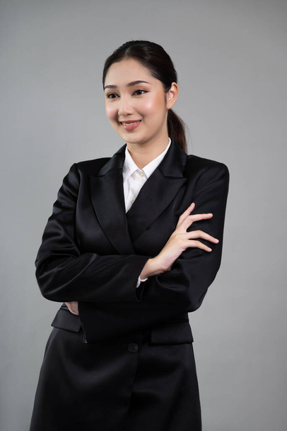Selbstbewusste junge Geschäftsfrau steht isoliert vor einem Hintergrund und posiert im formellen schwarzen Anzug. Bürokauffrau oder Manager mit intelligentem und professionellem Auftreten. Enthusiastisch - Foto, Bild