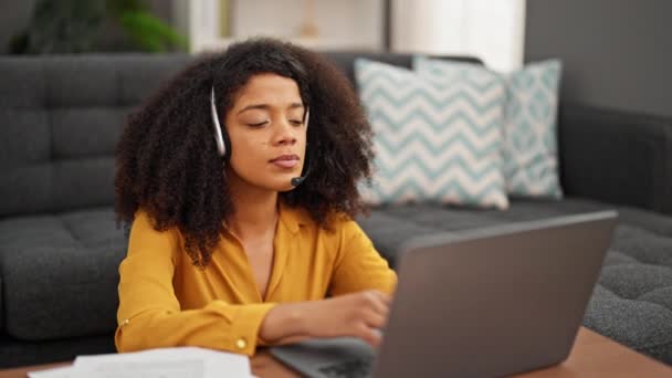 Femme afro-américaine agent du centre d'appels souriant travailler sortir casque relaxant à la maison - Séquence, vidéo