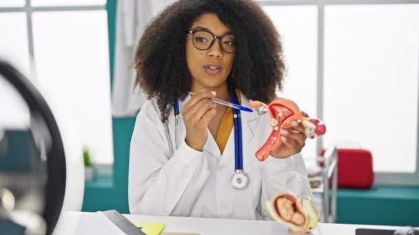 African american woman gynecologist doctor recording video tutorial of uterus at clinic - Footage, Video