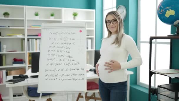 Молода вагітна жінка вчителька викладає математичний урок, що стоїть на руках схрещений жест у класі - Кадри, відео