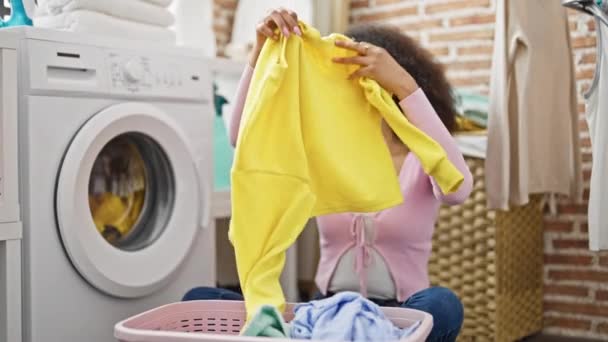Afrikai amerikai nő mosás ruhák összecsukható ruhát a mosókonyhában - Felvétel, videó