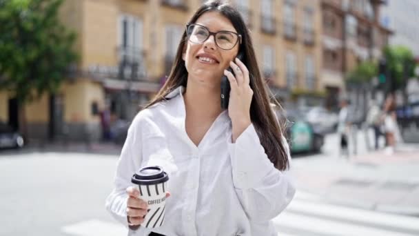 Młoda, piękna latynoska kobieta uśmiecha się szczęśliwa rozmawiając przez telefon na ulicach Madrytu - Materiał filmowy, wideo