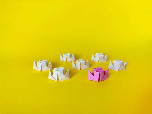 Origami boats. Group of white paper ships and one pink paper boat on a yellow background. Teamwork and leadership concept. - Photo, Image