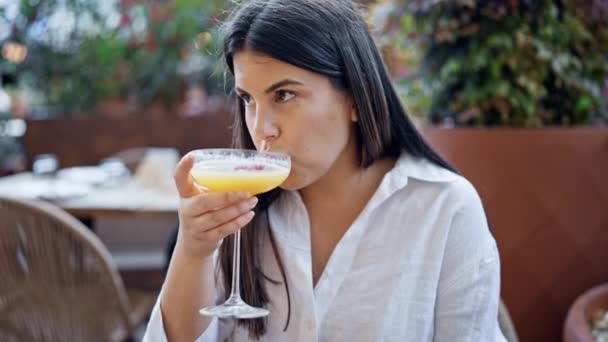 Νεαρή όμορφη ισπανόφωνη γυναίκα πίνει ένα τροπικό κοκτέιλ ποτό στη βεράντα του μπαρ - Πλάνα, βίντεο