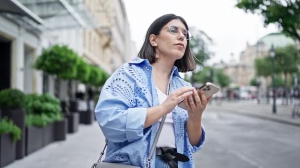 Νεαρή όμορφη ισπανόφωνη γυναίκα συναντά ένα φίλο χρησιμοποιώντας smartphone στους δρόμους της Βιέννης - Πλάνα, βίντεο
