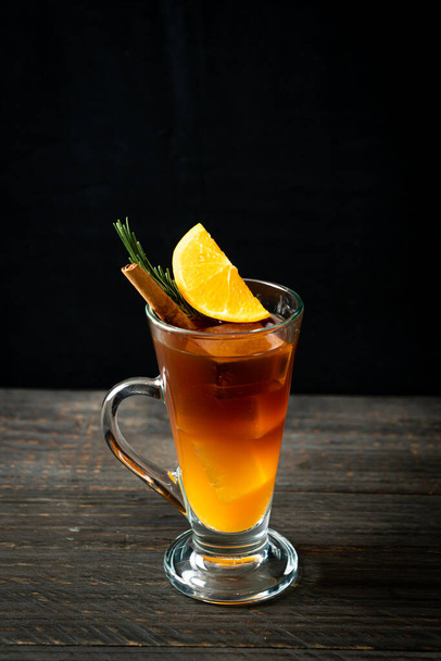 A glass of iced americano black coffee and layer of orange and lemon juice decorated with rosemary and cinnamon - Photo, image