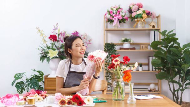 Flower shop concept, Vrouwelijke bloemist glimlach en houdt kleurrijke bloem boeket met papier en lint. - Foto, afbeelding
