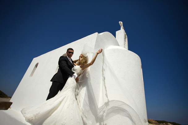 Ο νεαρός υπέροχο ζευγάρι όμορφη γυναίκα από όμορφος άντρας που αφορούν την ολόλευκη εκκλησία στην Ελλάδα - Φωτογραφία, εικόνα