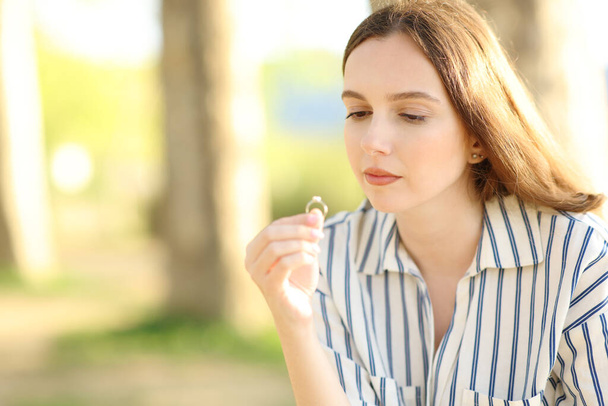 Pensive fiancee looking at engagement ring alone in nature - 写真・画像