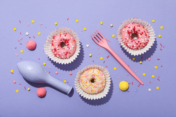 Mor arka planda donut, balon ve çatal, üst manzara - Fotoğraf, Görsel