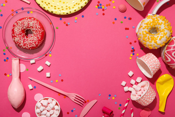 Donuts, auriculares y artículos de fiesta sobre fondo rosa, espacio para texto - Foto, Imagen