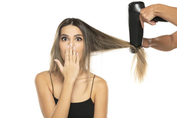 positively surprised young woman drying her hair on white studio background - Photo, Image