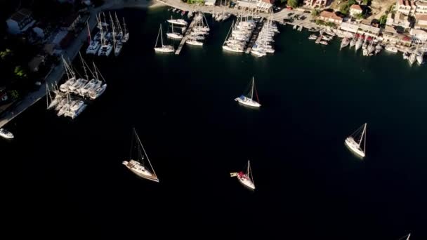 Marine port for yacht. Aerial top view of boats and yachts in marina from above. Yacht parking. Summer sea cruise on ship at green mountains island. White yacht . Sailboat. Luxury cruise trip. - Felvétel, videó