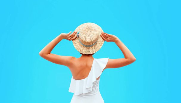 Placez le dos de la femme caucasienne dans le maillot de bain blanc assis près de la piscine (ou de la mer ou de l'océan) dans le chapeau de paille le jour d'été. Été, détente, bien-être, concept de loisirs - Photo, image