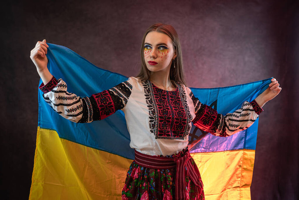 Портрет грустной украинки носит национальную одежду с синим и желтым флагом. Концепция свободы неприкосновенности украинского народа.   - Фото, изображение