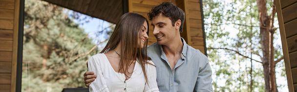 banner, gelukkig man knuffelen vrolijke vrouw terwijl zitten op de veranda, romantisch paar, vakantiehuis - Foto, afbeelding