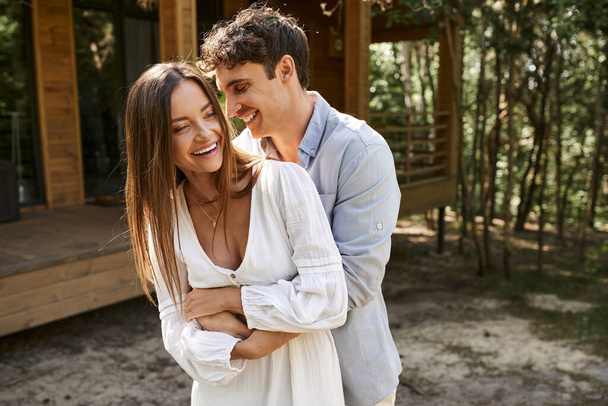 rire, homme heureux embrassant femme gaie en robe de soleil près de la maison de vacances, amour d'été, romance - Photo, image