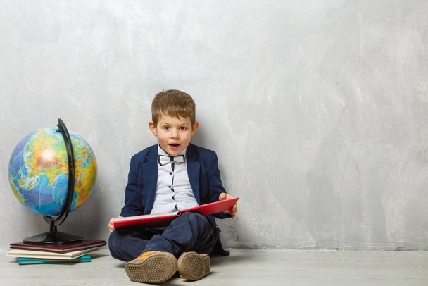 A little schoolboy, studying . A male child sitting on the floor - Photo, Image
