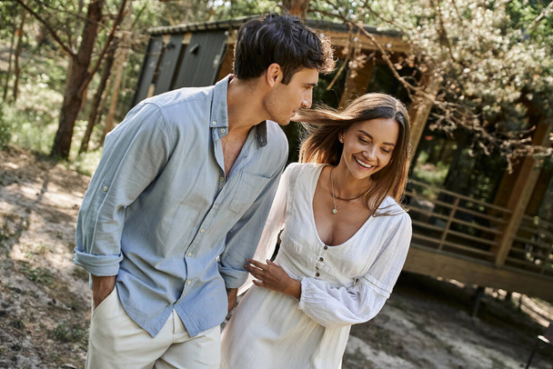 donna felice che si tiene per mano con il fidanzato, coppia positiva che cammina vicino alla casa estiva nella foresta, amore - Foto, immagini