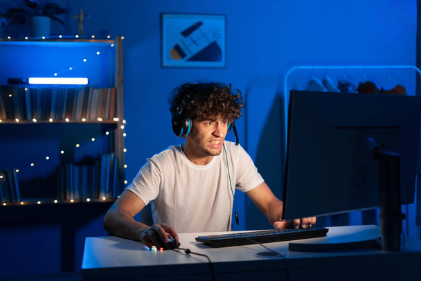 Arabische Wutbürger spielen Videospiele am Computer mit Neonlicht und blicken mit beängstigendem Gesicht auf den Monitor. Emotionales Videospiel. Kopierraum - Foto, Bild