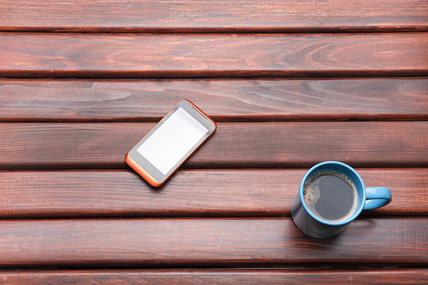 чашка кави і телефон на столі
 - Фото, зображення