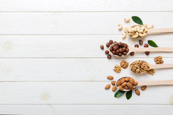 mixed nuts in white wooden spoon. Mix of various nuts on colored background. pistachios, cashews, walnuts, hazelnuts, peanuts and brazil nuts. - Φωτογραφία, εικόνα