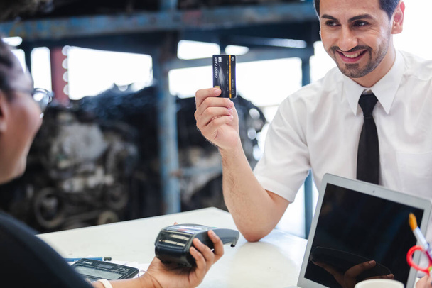 Male customers paying by credit card at counter in auto parts stores. business warehouse motor vehicle. Second-hand car parts sales center, staff accepting money from customers. - Valokuva, kuva